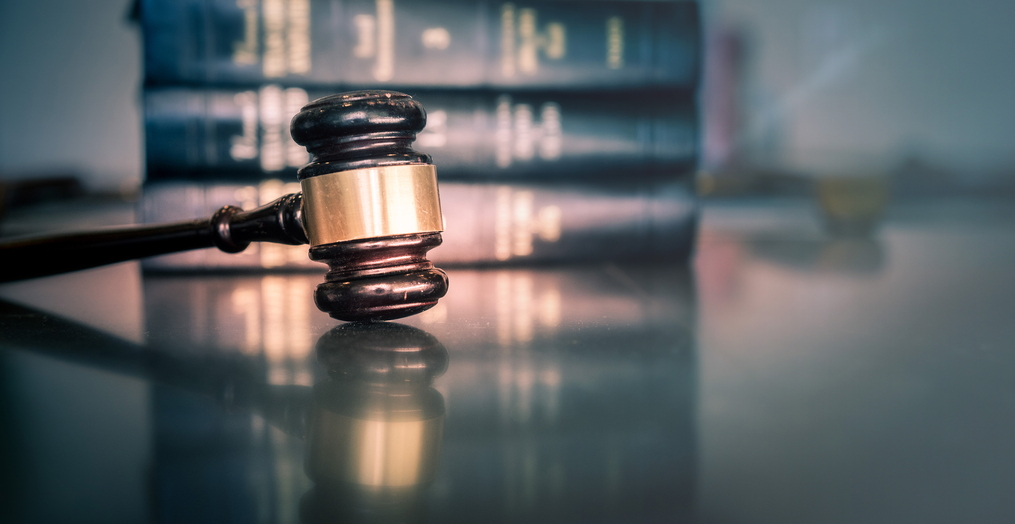 A judge's gavel sitting on a desk in front of a stack of books